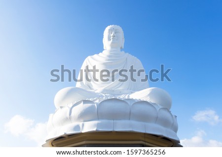 Statue, a monument to Buddha in Vietnam, in Nha Trang in sunshine on the background of clear blue sky. Buddhism, Buddha worship. A place for prayer and meditation.