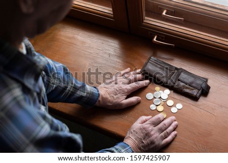 Hands of an old man and counting money, coins. The concept of poverty, low income, austerity in old age. Royalty-Free Stock Photo #1597425907