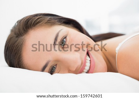 Close-up portrait of a pretty smiling young woman resting in bed