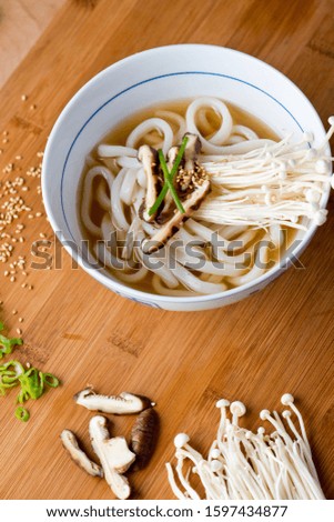 Udon noodle soup. Japanese udon noodles with beef broth, shitake, enoki mushrooms, scallions, sesame oil and chili pepper. Classic Japanese cuisine udon noodles with beef broth and shitake mushrooms.