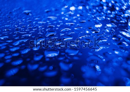 Abstract background in trendy blue neon color - drops of water close-up. Macro photo. Color year 2020 blue. Minimalism, copyspace.