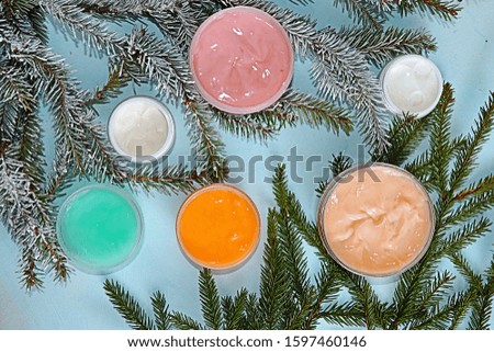 A set of creams for winter skin care on the background of fir branches, cosmetics for a modern woman, health care, spa procedures. Shopping concept, holiday sale, flat lay
