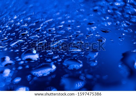 Abstract background in trendy blue neon color - drops of water close-up. Macro photo. Color year 2020 blue. Minimalism, copyspace.