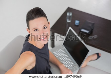 High angle view of a beautiful well dressed young woman with laptop on sofa at home