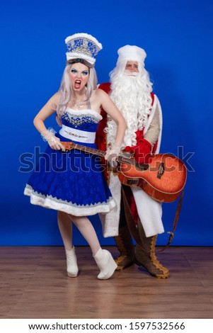 Duet of actors Emotional Santa Claus in a red coat with a guitar in his hands and a Snow Maiden in a blue suit with a microphone