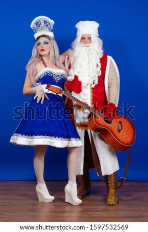 Duet of actors Emotional Santa Claus in a red coat with a guitar in his hands and a Snow Maiden in a blue suit with a microphone