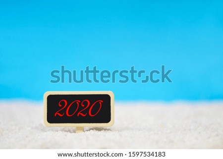 Billboard with the text "2020 " on the white sand beach over blue clear sky background used for your new year 2020, holiday and special day pattern design concept.