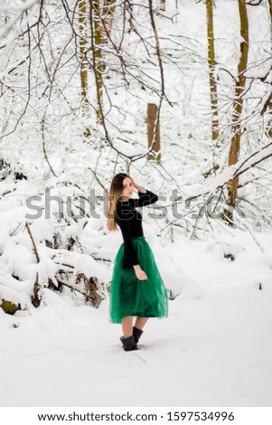 Girl in green skirt standing in winter forest