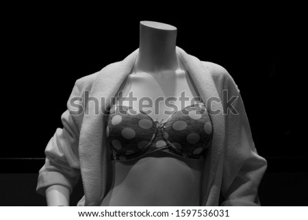 Black and white image of a headless female mannequin in a bikini top. 