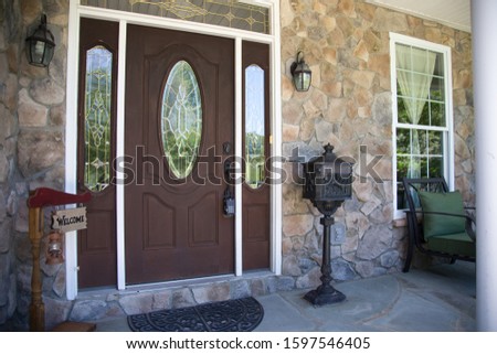 Beautiful exterior wooden front door contemporary classic architecture stone facade traditional sconces family model home real estate welcome sign iron letter mailbox private lot house