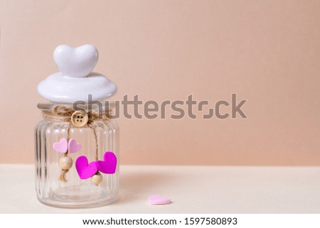 A glass can and a heart-shaped lid are on a light pink background. Close-up, copy space, layout design.