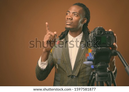 Young handsome African businessman against brown background