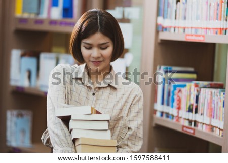 Young female student study in the school library. She is searching for knowledge in the library, process color.