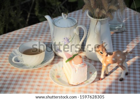 Tea time and cakes on in the table Outdoor ,Sweet color tablecloth with little deer.