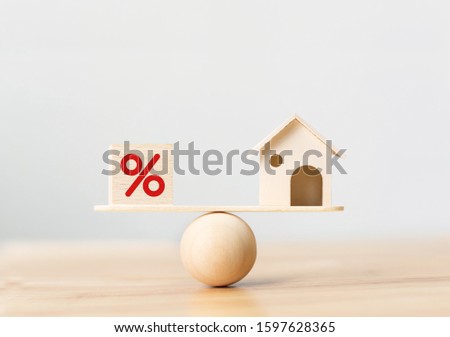 Interest rate financial and mortgage rates concept. Wooden home and cube block shape with icon percent on wood scales