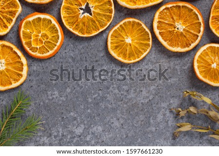 Christmas background mockup top view with copy space. Fir tree branches and dry oranges on dark background flat lay. Winter holiday frame. New Year's composition. Mockup sliced oranges with a crust.