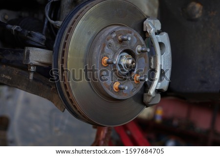 Disk brake car and car disk brake system service concept, Disc brake of the vehicle for repair, in process of new tire replacement. service by hand of mechanic man in car garage, Car disk, close up.