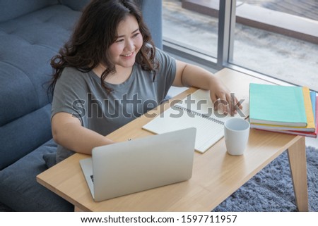 Overweight female. Plus size model. Big girl. Fat person. Chubby Asian woman Sitting and working in the living room. Freelancer. Online shopping. Work at home. E-commerce. Business. Lifestyle concept