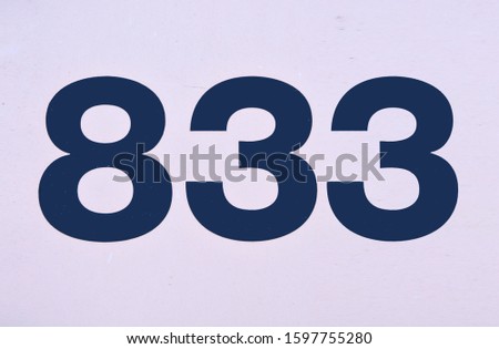 Dark colored number eight hundred thirty three (833) on a bright metal background. 