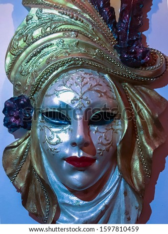 Venetian carnival mask with colorful hat hanging on wall