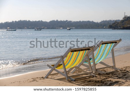 Vacation on the beach concept with two chairs on the white sand beach, Relaxing on seaside with approaching sea wave on the seashore in tropical island, Free copy space for your text.