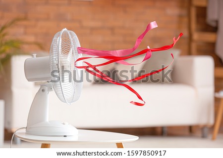 Electric fan with fluttering ribbons in room Royalty-Free Stock Photo #1597850917
