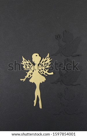 Photo of a golden fairy with three black angels, on a black background.