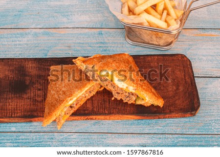 Stock image of Reuben Sandwich, classic served with corned beef, Swiss cheese, sauerkraut, thousand island dressing on grilled rye bread placed on wooden cutting board