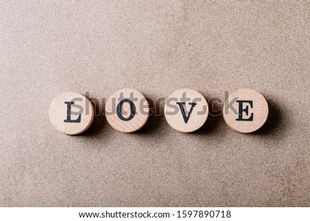 Word love made with wooden circle stamps over brown texture background. Top view, flat lay. Copy space