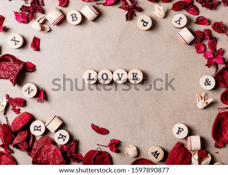 Word love made with wooden circle stamps with flowers over brown texture background. Top view, flat lay. Copy space