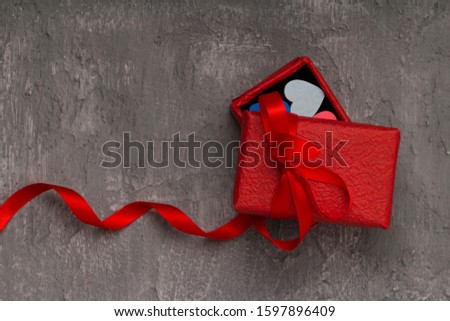 Valentines day background with hearts and a red gift box on concrete board . close up , copy space