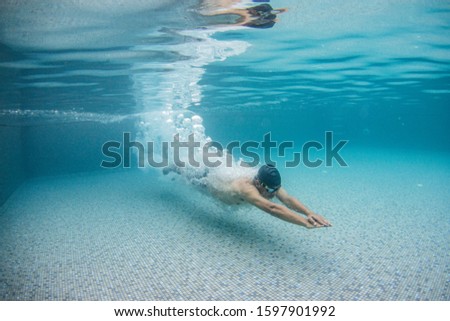 Underwater picture of swimming man in the pool.After jump