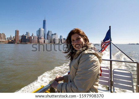 Portrait of happy woman on boat with Manhattan and the USA flag in the background.