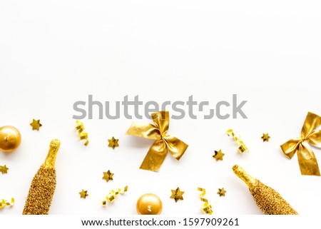 New Year background. Golden composition with champagne bottle and decorations on white desk top-down frame copy space