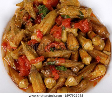 a Okra with red pepper and turkey spices on white plate on wooden bamya table for Hotel & Restaurant Orders and Menu and Internet and TV 