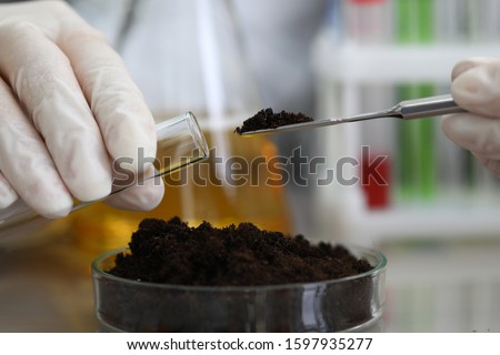 Female chemist in white protective gloves hold test tube against chemistry lab background closeup. Express research crop soil content of beneficial and harmful substances concept Royalty-Free Stock Photo #1597935277