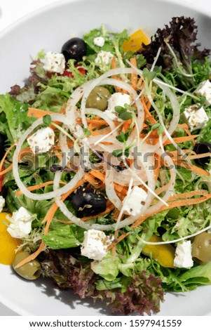 greek salad with feta cheese and olives with citrus vinaigrette on white table