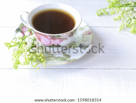 a cup of black coffee and a bouquet of lilies of the valley close-up.