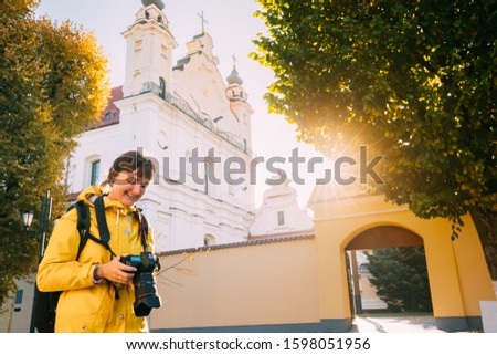 Pinsk, Brest Region, Belarus. Young Woman Tourist Lady Photograph Taking Pictures Near Cathedral Of Name Of The Blessed Virgin Mary. Famous Historic Landmarks. Sun Sunshine In Autumn Sunny Day