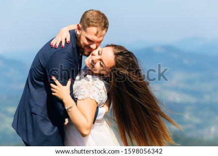 the newlyweds closed their eyes and gently hug. happy smiles of a couple in love against the background of the mountains