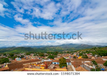 Landscape of city and mountains full of palm trees and flowers, under cloudy sky, sunny beautiful day, Trinidad, Cuba