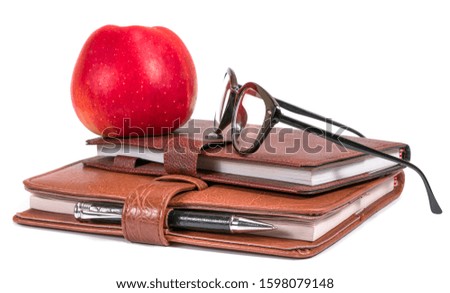 
glasses, notebooks and apple on a white background