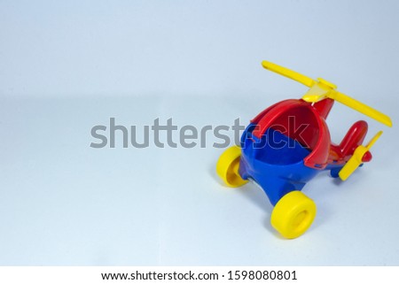 Children's toy, plastic red-blue helicopter with a yellow propeller and wheels on a gray fleecy background

