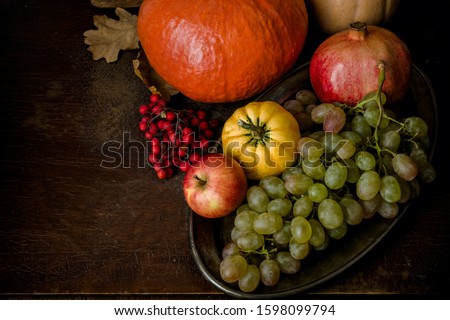 Autumn still life, pumpkin, green grapes, pomegranate, Apple on a metal tray, wooden background