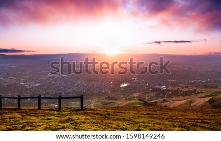 Sunset view of San Jose, part of Silicon Valley; hills starting to turn green visible in the foreground; San Francisco Bay Area, California