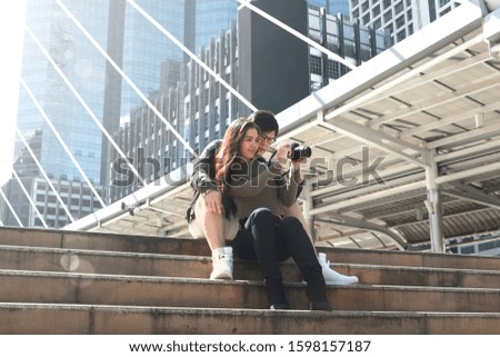 Young Asian tourist couple traveling together. Travelers with camera taking photo to keep in good memory during their journey trip. Concept of travel is discovering new places