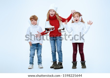 Three beautiful kids in winter clothes posing together at studio. White background. Winter fashion, winter activities. Christmas and New Year.