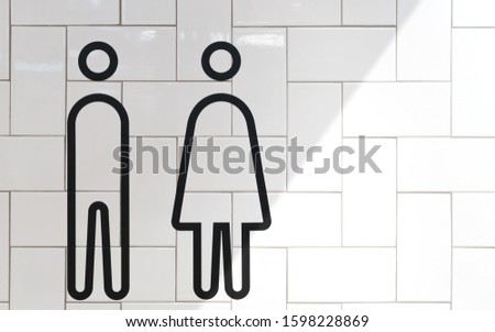 World toilet day - Modern and minimal design of toilet sign, black outline of men and women, on white tiles herringbone pattern walls in airport terminal, train station, hotel or shopping mall.