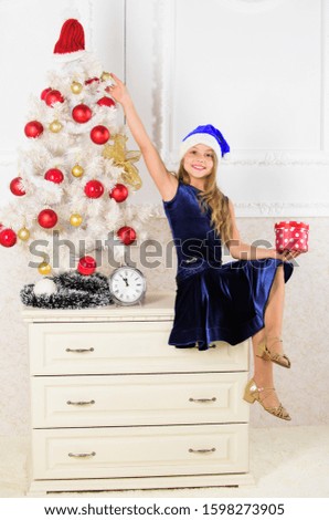 Merry christmas concept. Best for kids. Kid girl near christmas tree hold gift box. Little girl santa hat excited about gift. Child celebrate christmas at home. Time to open christmas gifts.