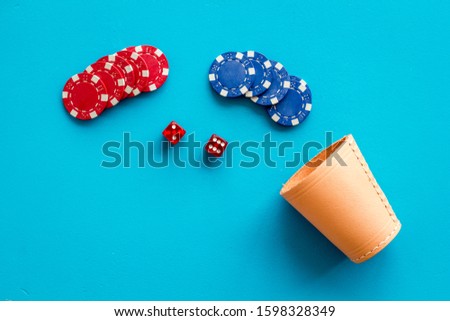 Poker hazard game concept. Chips, dices, cup for dice on blue background top-down copy space